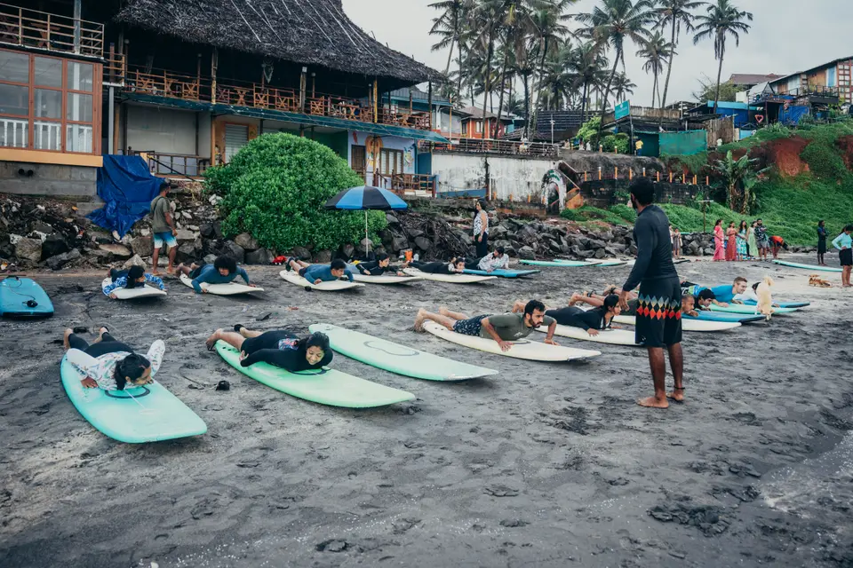 A surf class gathered on the sand at Edava beach, Varkala, boards down at the water line